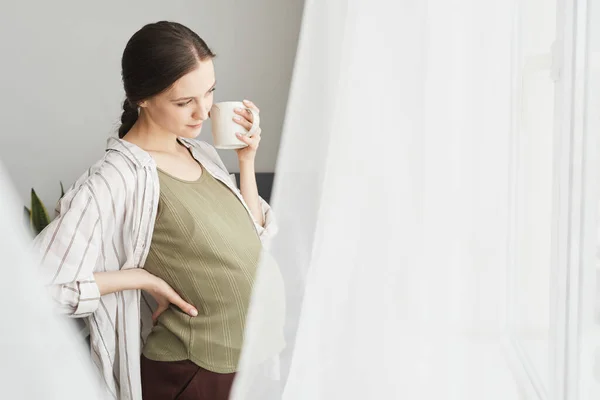 Young Pregnant Woman Looking Window Enjoying Cup Coffee — Zdjęcie stockowe