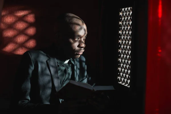 Sacerdote Africano Lendo Bíblia Enquanto Está Sentado Confessionário — Fotografia de Stock