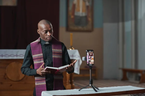 非洲牧师手持圣经 在网上用手机现场直播时表演 — 图库照片