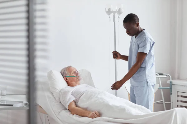 Porträtt Afroamerikanska Manliga Sjuksköterska Inrätta Dropp Vid Behandling Äldre Patient — Stockfoto