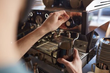 Close up of unrecognizable barista operating coffee machine while making fresh coffee in cafe or coffee shop, copy space