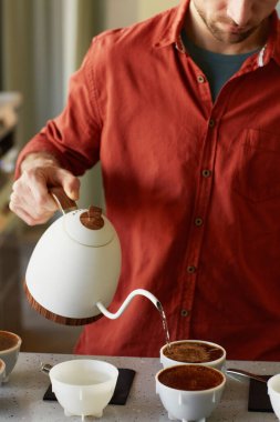 Barda bardaklara kahve dolduran tanınmayan erkek baristanın dikey yakın çekimi.