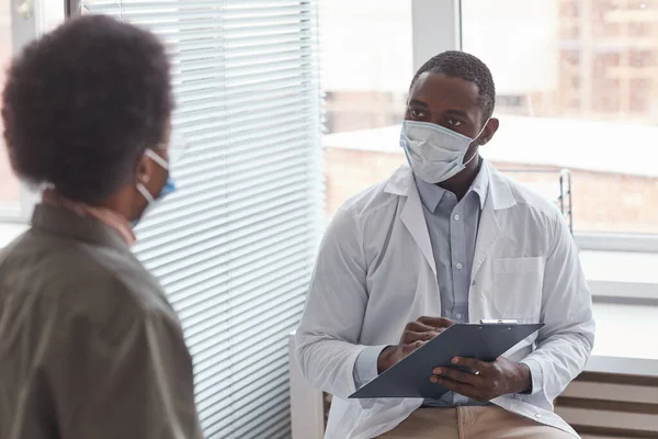 Afrikaanse Arts Beschermende Masker Praten Met Zijn Patiënt Tijdens Haar — Stockfoto