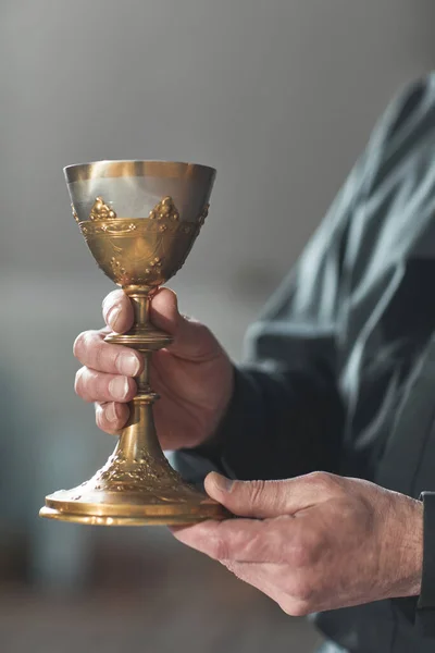 牧师站在教堂时端着酒杯的特写镜头 — 图库照片