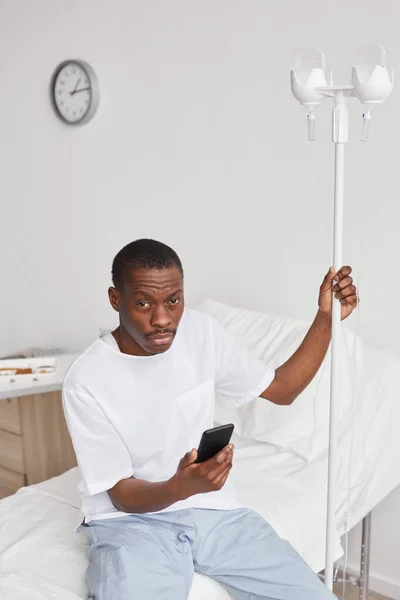 Hastane Odasında Serumlu Akıllı Telefon Kullanan Genç Afro Amerikan Bir — Stok fotoğraf