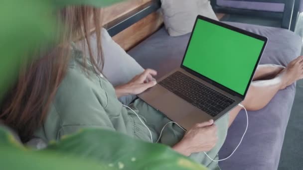 高角度的自由职业者 脚踏在沙发上 用绿色屏幕笔记本电脑在键盘上打字 — 图库视频影像