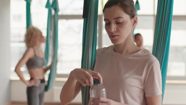 Tilting Young Caucasian Woman Drinking Water Bottle Break Aerial Yoga — Stockvideo