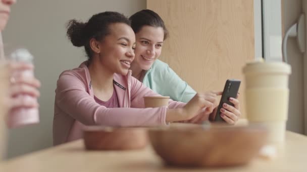 Kafedeki Masada Oturan Akıllı Telefon Kullanan Konuşan Gülümseyen Iki Genç — Stok video