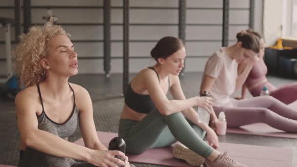 Mellomlang Tid Fire Unge Trøtte Idrettskvinner Som Sitter Yogamatter Gymsalen – stockvideo