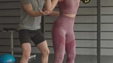 Tozluk ve hasır bluz giyen, halterle çömelmiş, genç erkek koçun onu sigortalaması...