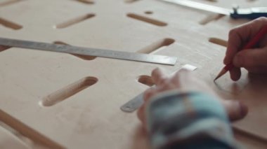 Tanımlanamayan erkek marangozun kalem kullanarak ahşap bankın üzerine plan çizmesini kapatın.