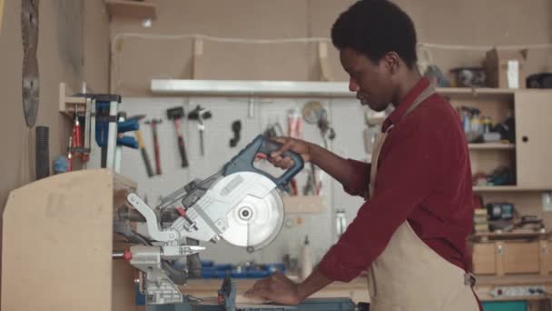 Tiro Médio Carpinteiro Africano Masculino Usando Avental Usando Serra Circular — Vídeo de Stock