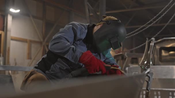 과붉은 장갑을 착용하고 차고에서 물체를 용접하는 알아볼 수없는 노동자 — 비디오