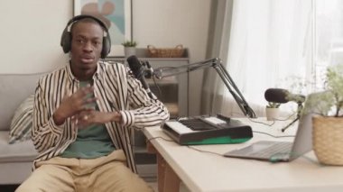 Kulaklık takan genç Afrikalı Amerikalı erkek müzisyenlerin evdeki m-ses keystation 'ında oturup kameraya bakarken rap yapmaları ve el kol hareketi yapmaları.
