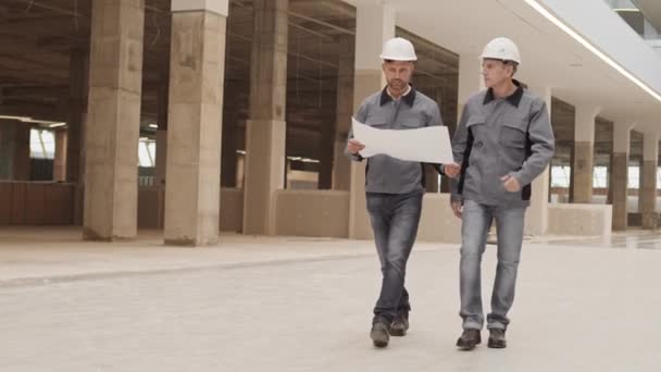 Weite Verfolgung Von Zwei Männlichen Kaukasischen Bauarbeitern Mit Weißen Hüten — Stockvideo