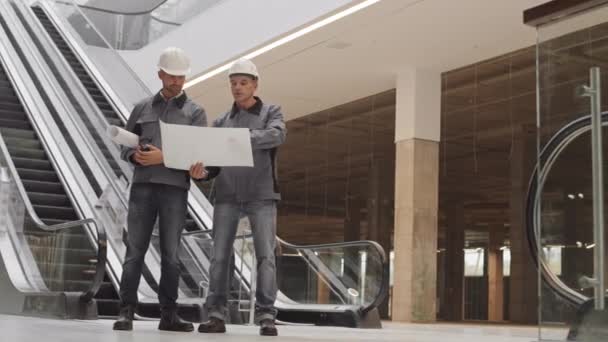 근로자용 헬멧을 코카서스 기술자가 쇼핑몰 에스컬레이터 프로젝트 문서를 — 비디오