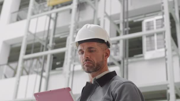 Umkippen Eines Kaukasischen Männlichen Bauarbeiters Arbeiterjacke Und Harter Mütze Vordergrund — Stockvideo
