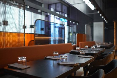 Bistro kafe koltukları arasında farklı desenli paneller: peçete ve bardaklarla servis edilen masalar