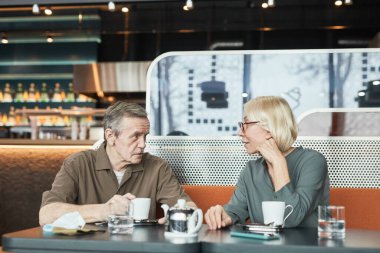 Masada oturan bıyıklı olgun bir adam kafeteryada çay içerken meraklı kız arkadaşına hikaye anlatıyor.