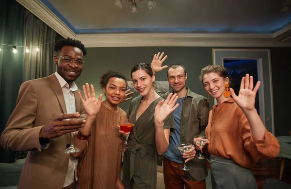 Çevrimiçi partiden keyif alırken kameralara el sallayan bir grup neşeli genç.