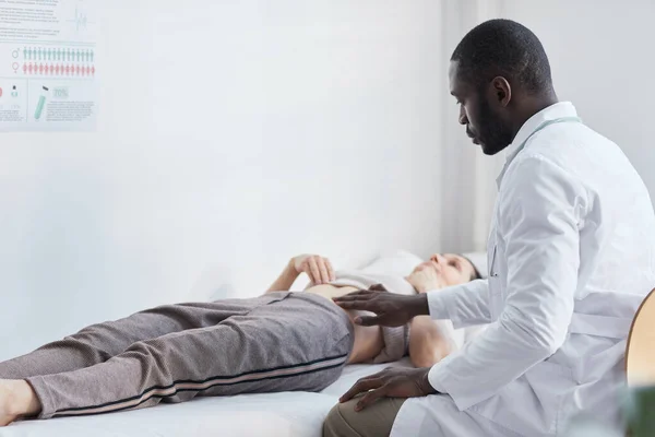 Médico Africano Bata Blanca Examinando Paciente Mientras Yacía Sofá Durante —  Fotos de Stock