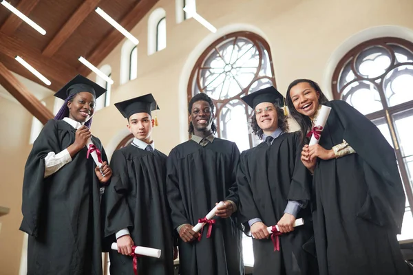 Vista Bajo Ángulo Grupo Multiétnico Jóvenes Que Usan Túnicas Graduación — Foto de Stock