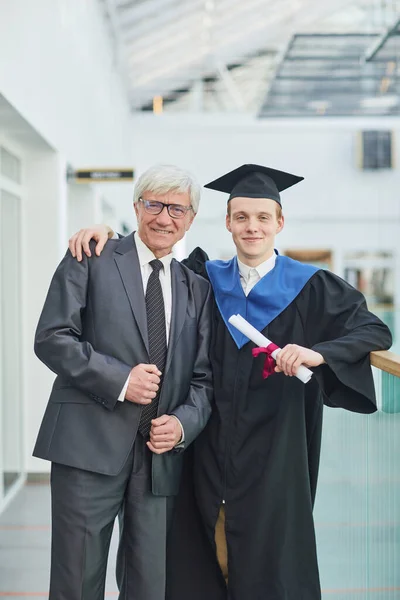 Pionowy Portret Uśmiechniętego Młodzieńca Pozującego Ojcem Podczas Ceremonii Ukończenia Szkoły — Zdjęcie stockowe