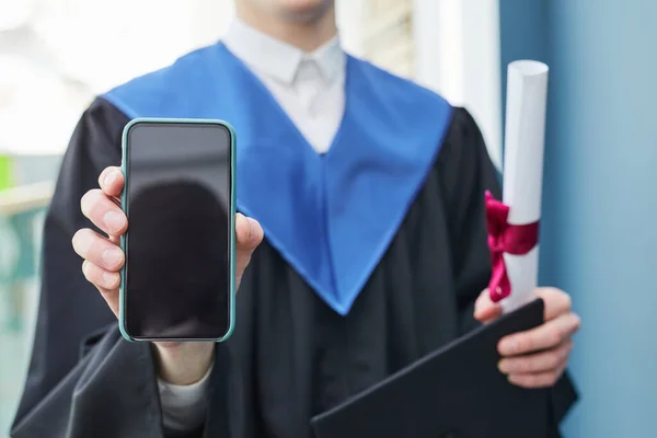 式典中にカメラに空白の画面を持つ認識できない大学卒業生の保持スマートフォンの閉じる コピースペース — ストック写真