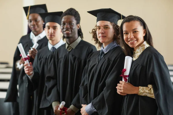 Grupo Multiétnico Jóvenes Felices Con Batas Graduación Parados Fila Mirando —  Fotos de Stock