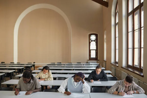 Okulun Oditoryumunda Masa Başında Otururken Sınava Giren Çeşitli Öğrencilerin Geniş — Stok fotoğraf