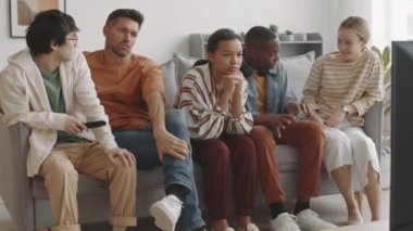 Oturma odasındaki kanepede oturmuş televizyon seyreden iki çift sıkılmış bir ırk kızı gibi konuşuyorlar.