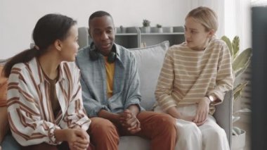 Oturma odasındaki kanepede oturmuş sohbet eden orta boylu, güzel arkadaşlar.