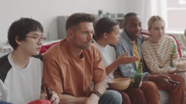 Oturma odasındaki kanepede oturmuş sohbet eden beş farklı genç var.