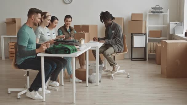 Logaritmo Completo Equipe Voluntários Diversificada Conversando Enquanto Sentados Mesa Embalando — Vídeo de Stock