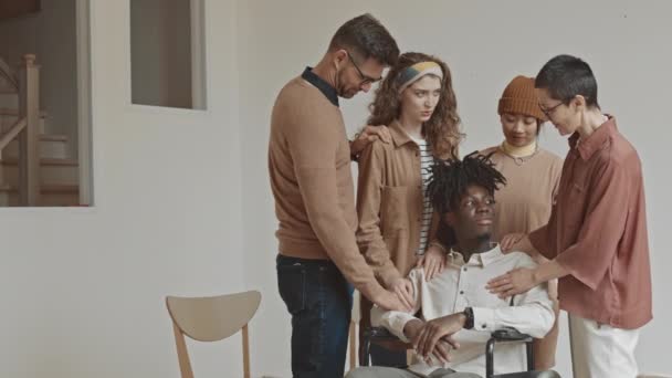 車椅子の若いアフリカ系アメリカ人男性が彼を支えている友人のグループの中低速 — ストック動画