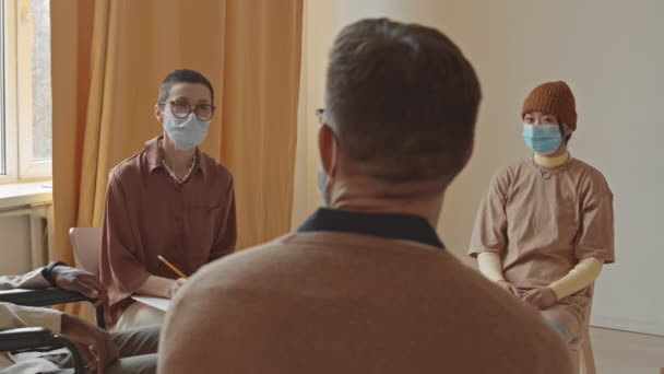 顔マスクを纏った女性専門家の話を聞く認知できない男の後見中出し集団治療セッション — ストック動画