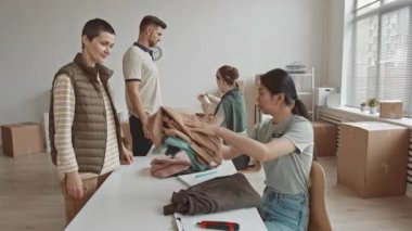 Kadın gönüllülerin, kar amacı gütmeyen yardım kuruluşlarına gelen insanlara konserve ve yiyecek dağıtan orta boy bir yavaşlama.