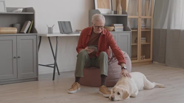 Voller Tatendrang Streichelt Ein Aufmerksamer Älterer Hundebesitzer Mit Digitalem Tablet — Stockvideo
