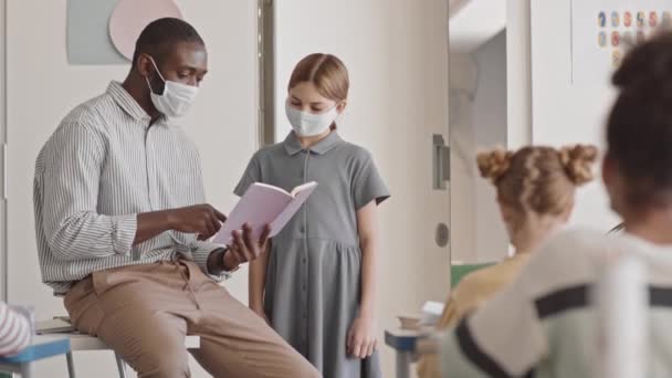 Średnie Spowolnienie Męskiego Afro Amerykańskiego Nauczyciela Sprawdzającego Pracę Domową Uczennicy — Wideo stockowe