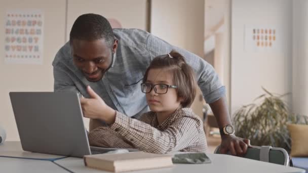 若い男性の中低速アフリカ系アメリカ人教師とノートパソコンの画面で宿題やタスクを議論見て5年生 — ストック動画