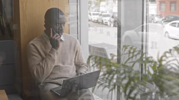 Сквозной Снимок Современного Афроамериканца Умной Повседневной Одежде Разговаривающего Телефону Сидя — стоковое видео