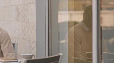 Afro-Amerikan işadamının şehir merkezindeki kafenin dışındaki masada otururken telefonla konuştuğu orta PAN görüntüsü.