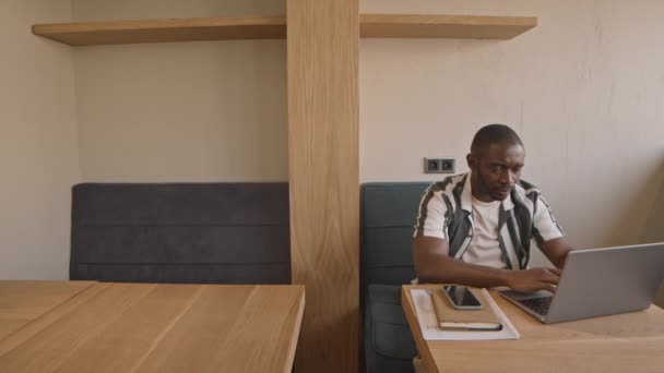 Średnie Ujęcie Młodego Afroamerykanina Luźnej Koszuli Paski Piszącego Laptopie Przy — Wideo stockowe