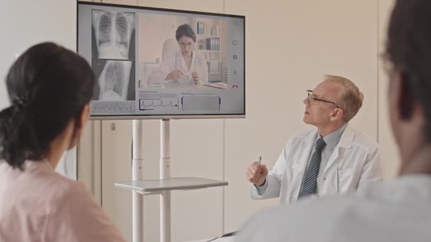 年轻女性放射学家通过视频聊天和同事一起检查胸部X光 慢吞吞地与同事交谈 — 图库视频影像