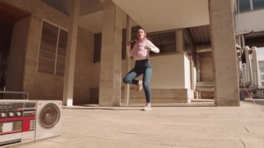 Klasik kaset teyplerinin geniş açısında kaset çalar, güneşli bir günde dans eden genç, beyaz bir kadını takip ediyor.