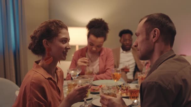 多民族の友人と夕食のテーブルに座っている間に会話を持つ若いロマンチックなカップルのサイドビュー中出し — ストック動画