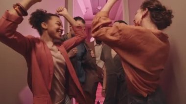 Çok ırklı fantezi gruplarından oluşan orta yaşlı bir grup ev partisinde dans ederken Afro-Amerikalı genç adam kamerada şık dans hareketleri yapıyor.
