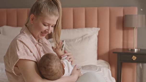 침대에 아기에게 모유를 먹이며 말하는 여성의 — 비디오