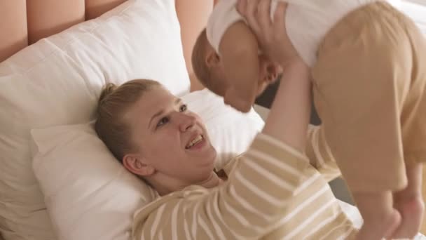 어머니의 침대에 아이를 올리고 아래로 웃으면서 — 비디오