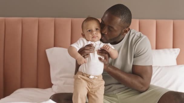 Mittellang Sitzt Der Junge Afrikanische Vater Auf Dem Bett Stützt — Stockvideo